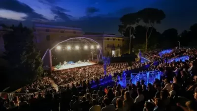 Night concert in the open-air amphitheater during the Nits d'Occident festival in Barcelona with the audience filling the illuminated stands.
